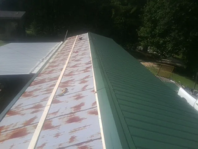 Old rusted panels beside newly installed green metal roofing — Wind Damage Roof Repair by Roofing Brothers in Bethany